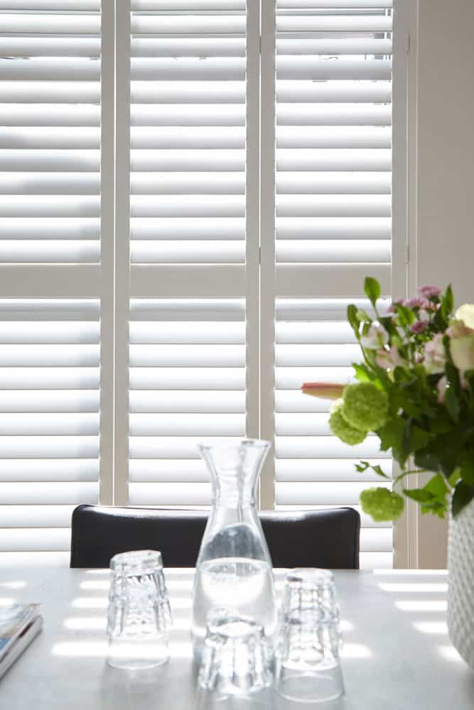 White Shutter Beside Table With Plants — Timber Tec Shutters In Ballina, NSW